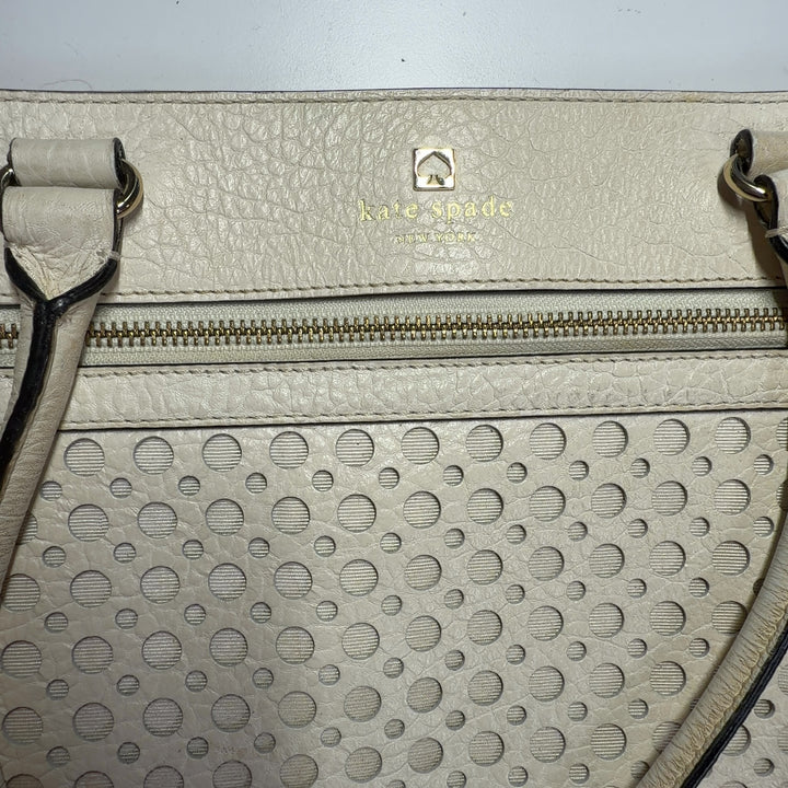 Tag view of cream Kate Spade perforated leather shoulder tote bag showing structured silhouette
