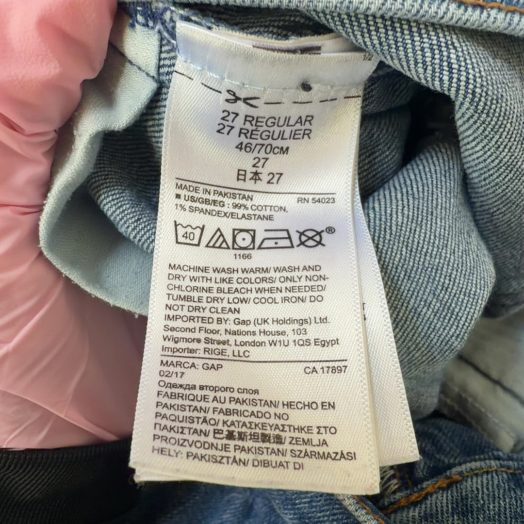 Tag view of blue denim shorts showing distressed rip detail on thigh and classic denim construction