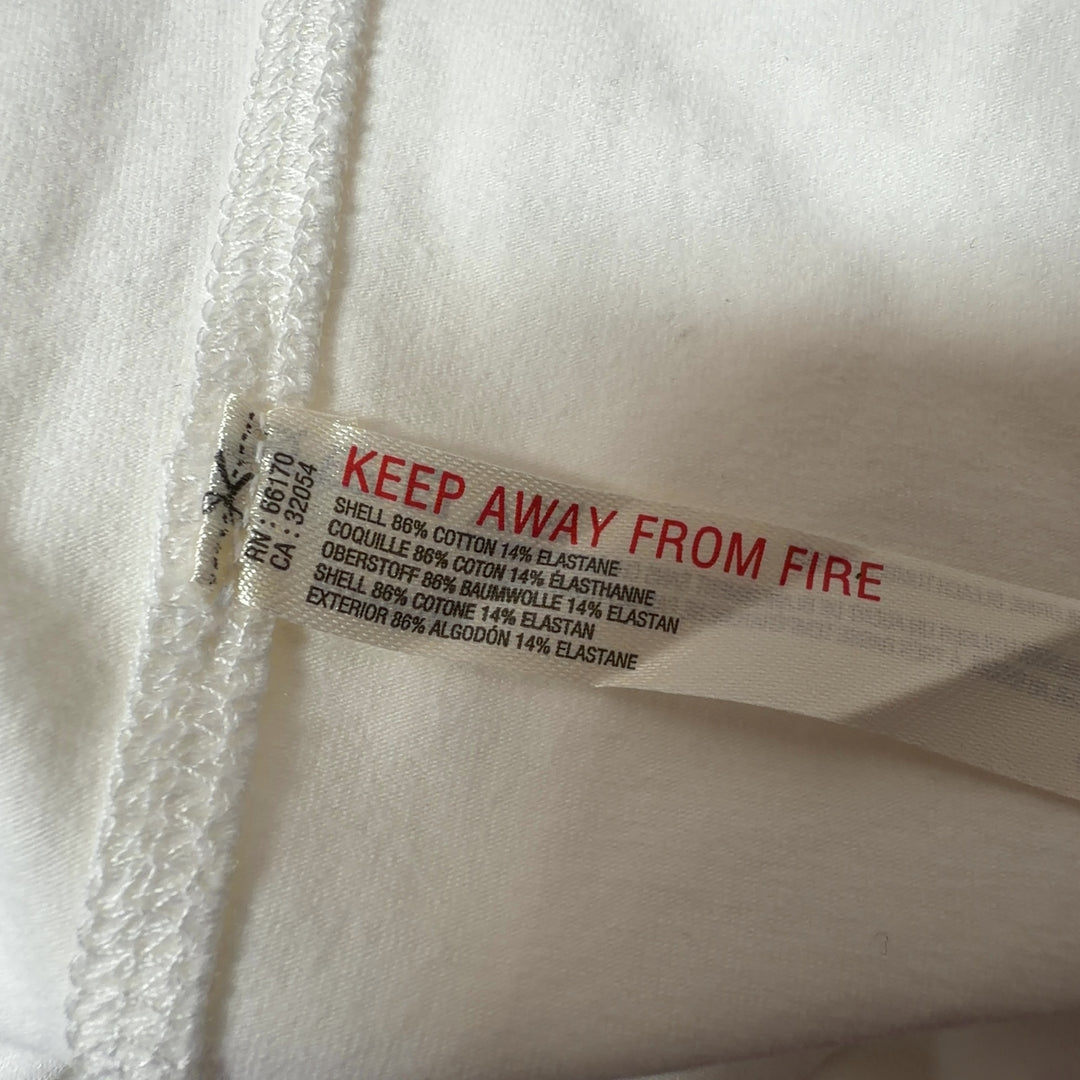 Tag view of cream tank top showing fitted silhouette and black button detailing