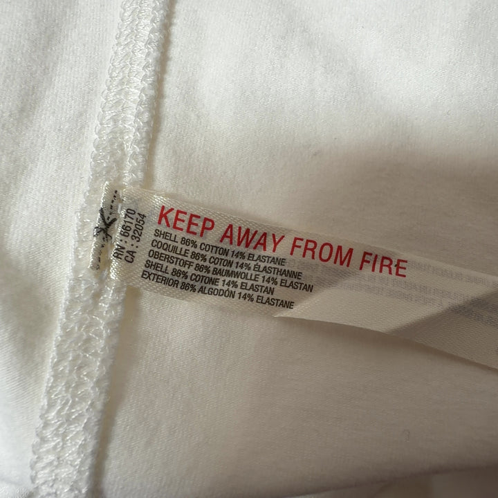 Tag view of cream tank top showing fitted silhouette and black button detailing
