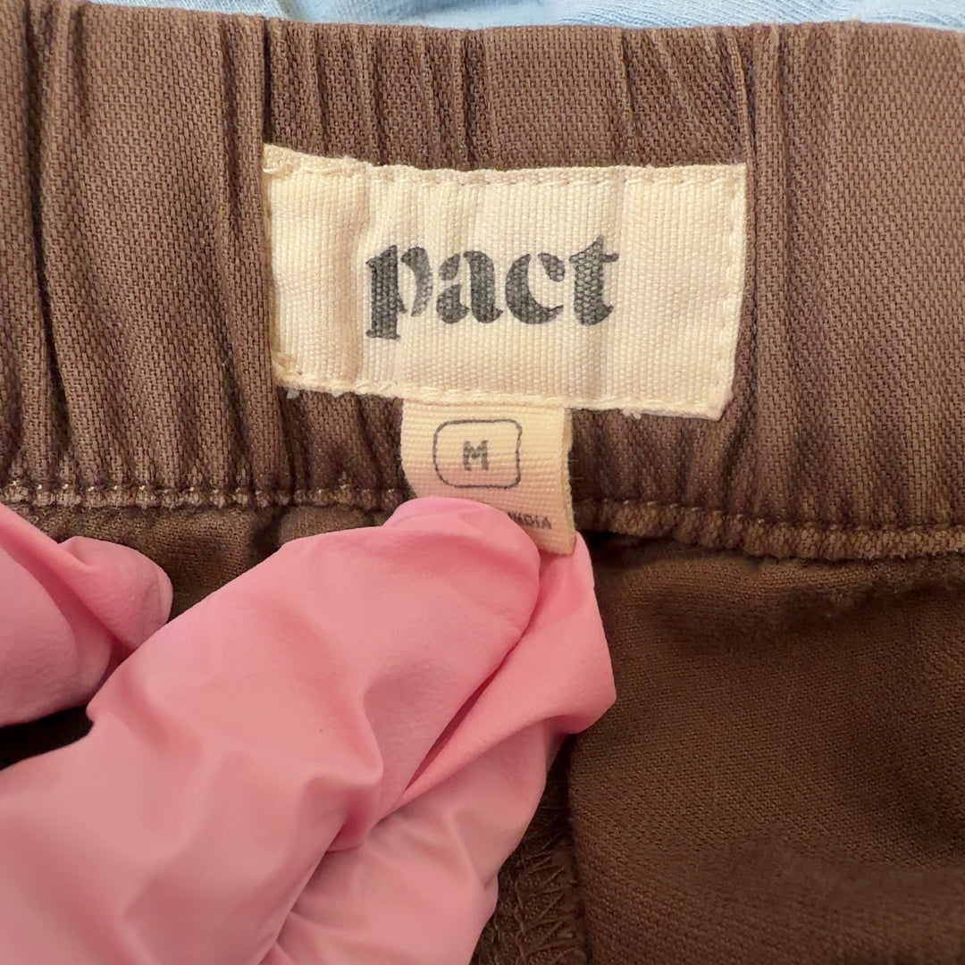 Tag view of brown organic cotton drawstring pants showing relaxed silhouette and functional back pockets