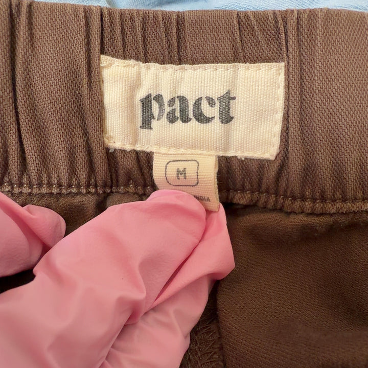 Tag view of brown organic cotton drawstring pants showing relaxed silhouette and functional back pockets