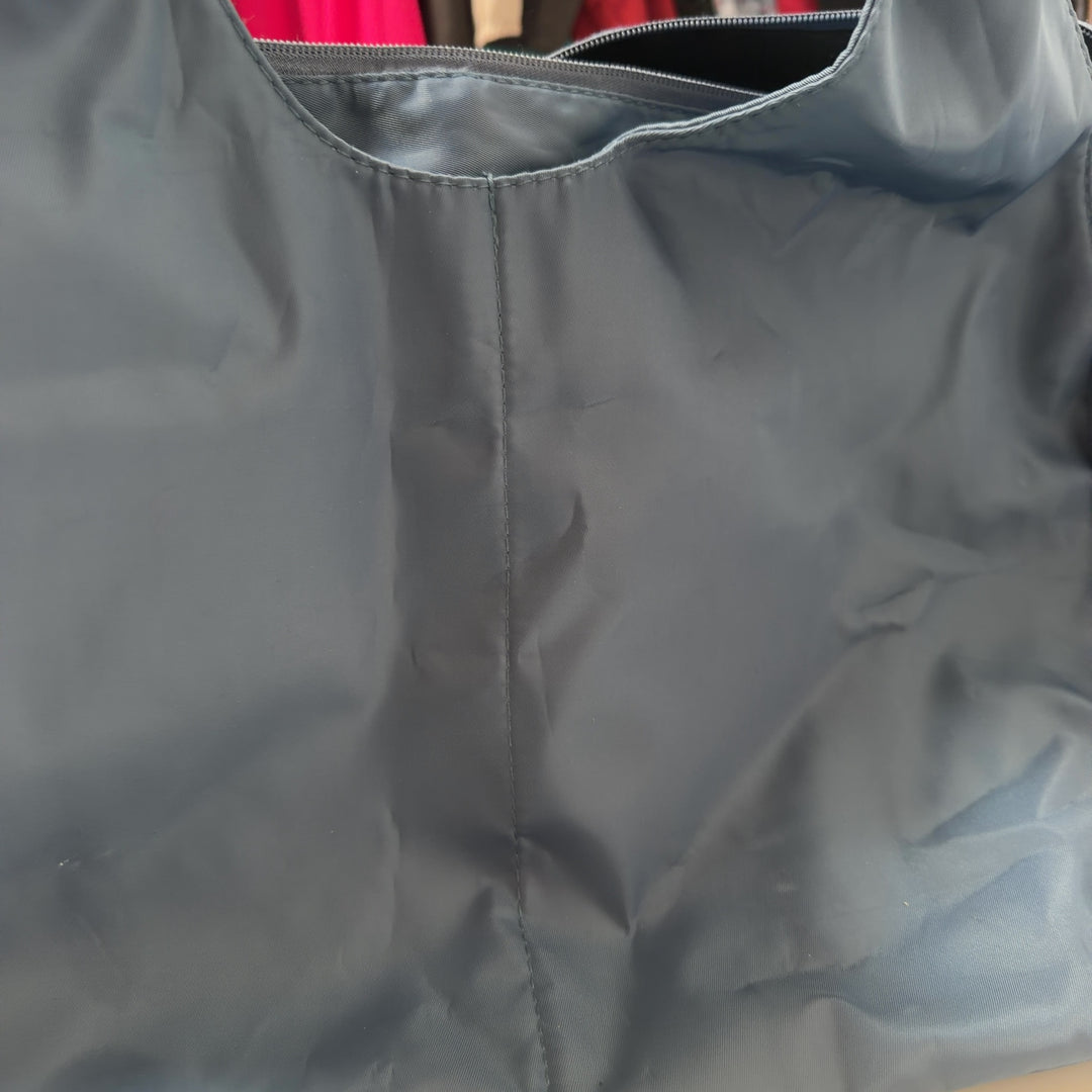 Tag view of SilkRoll blue slouchy hobo tote bag worn on shoulder, displaying relaxed silhouette and soft fabric drape