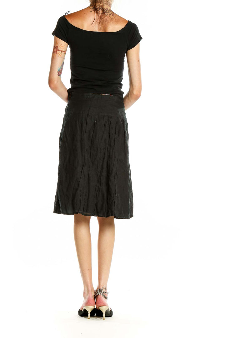 Side view of black flowy midi skirt with woman wearing black top