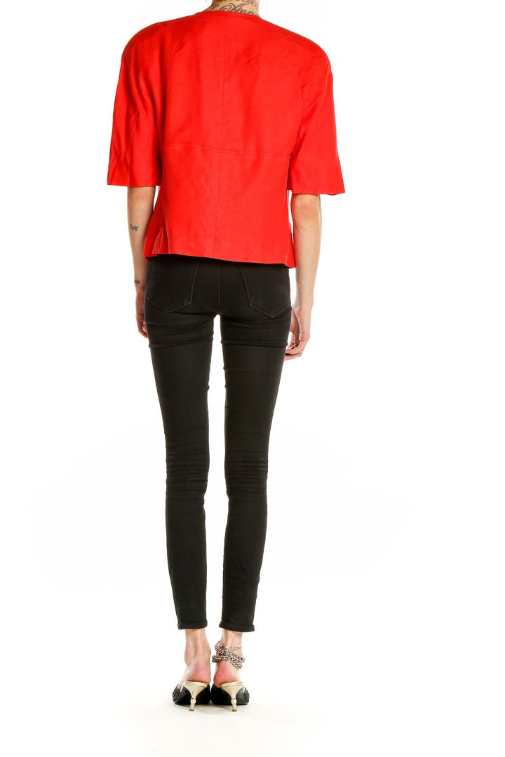 Side view of red Louis Feraud cropped jacket on model with black pants