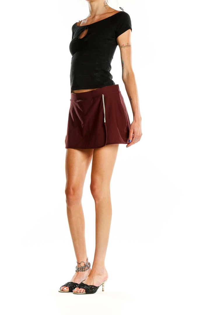 Front view of burgundy Nike athletic skort with zippered pockets