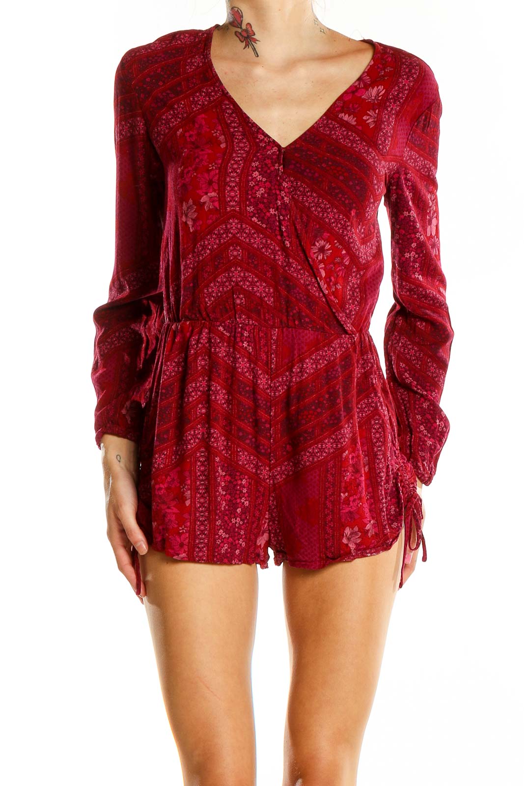 Front view of red floral Kendall + Kylie romper with V-neck and long sleeves