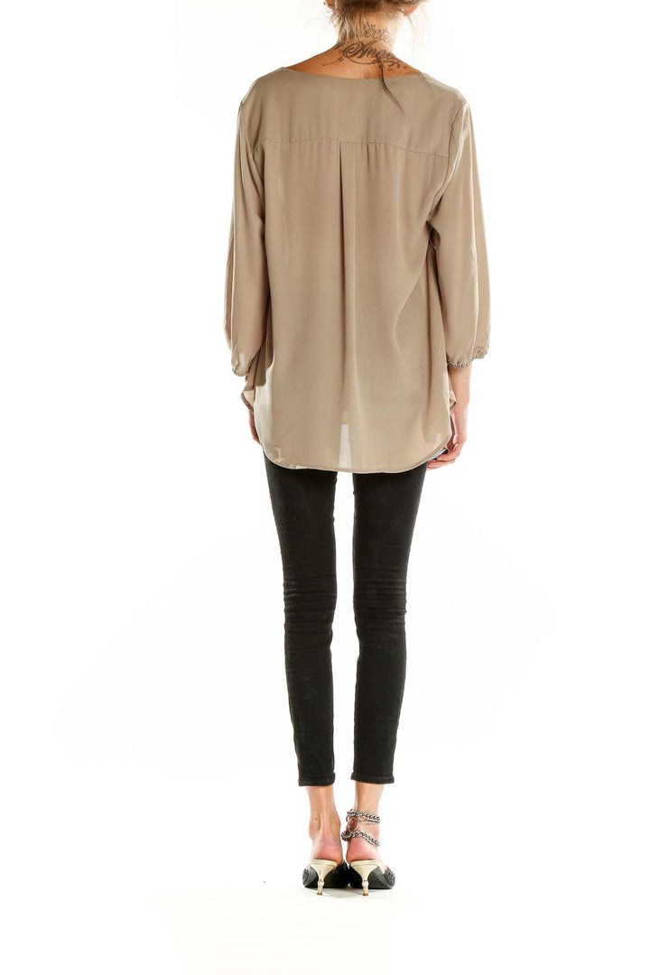 Back view of beige Pleione blouse showing relaxed fit and length