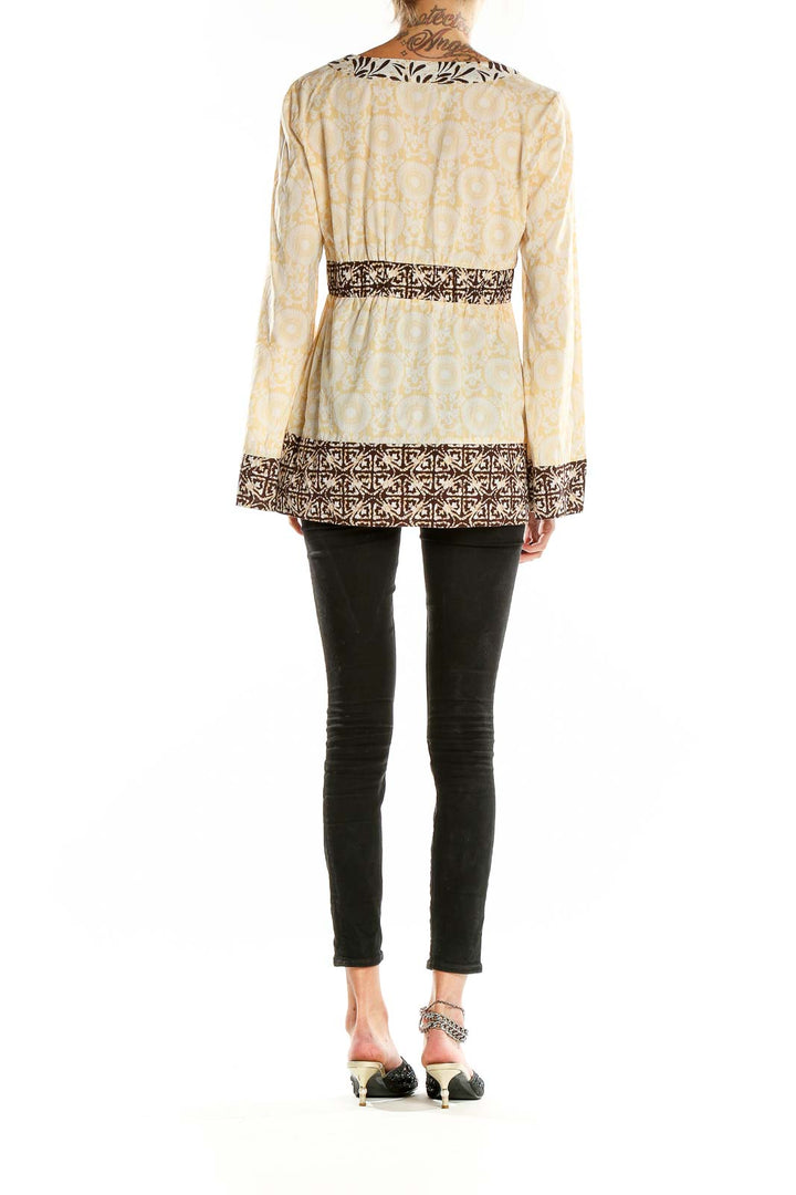 Back view of cream floral print MICHAEL Michael Kors tunic showing bell sleeves and geometric hem design