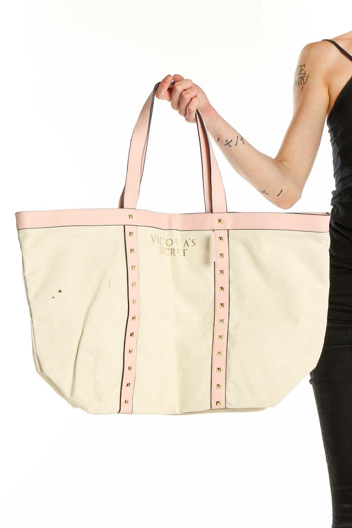 Victoria's Secret beige canvas tote bag with pink trim and gold studs, front view